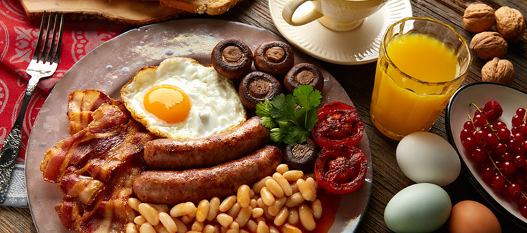 Englisches Frühstück in Dover mit Würstchen, Ei, Bohnen, Speck, Pilzen und gegrillten Tomaten
